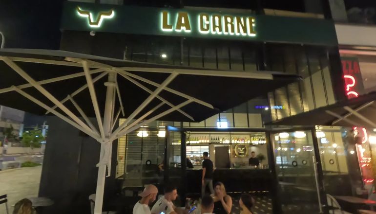 תמונה מבחוץ של אנשים יושבים במסעדת לה קרנה